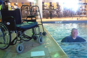 Dennis walking in water, abandoned wheelchair beside him.